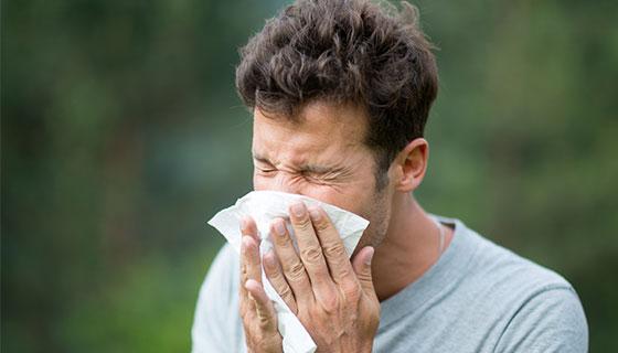 man sneezing into a tissue