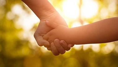 A child with finger deformities holds hands with their parent.